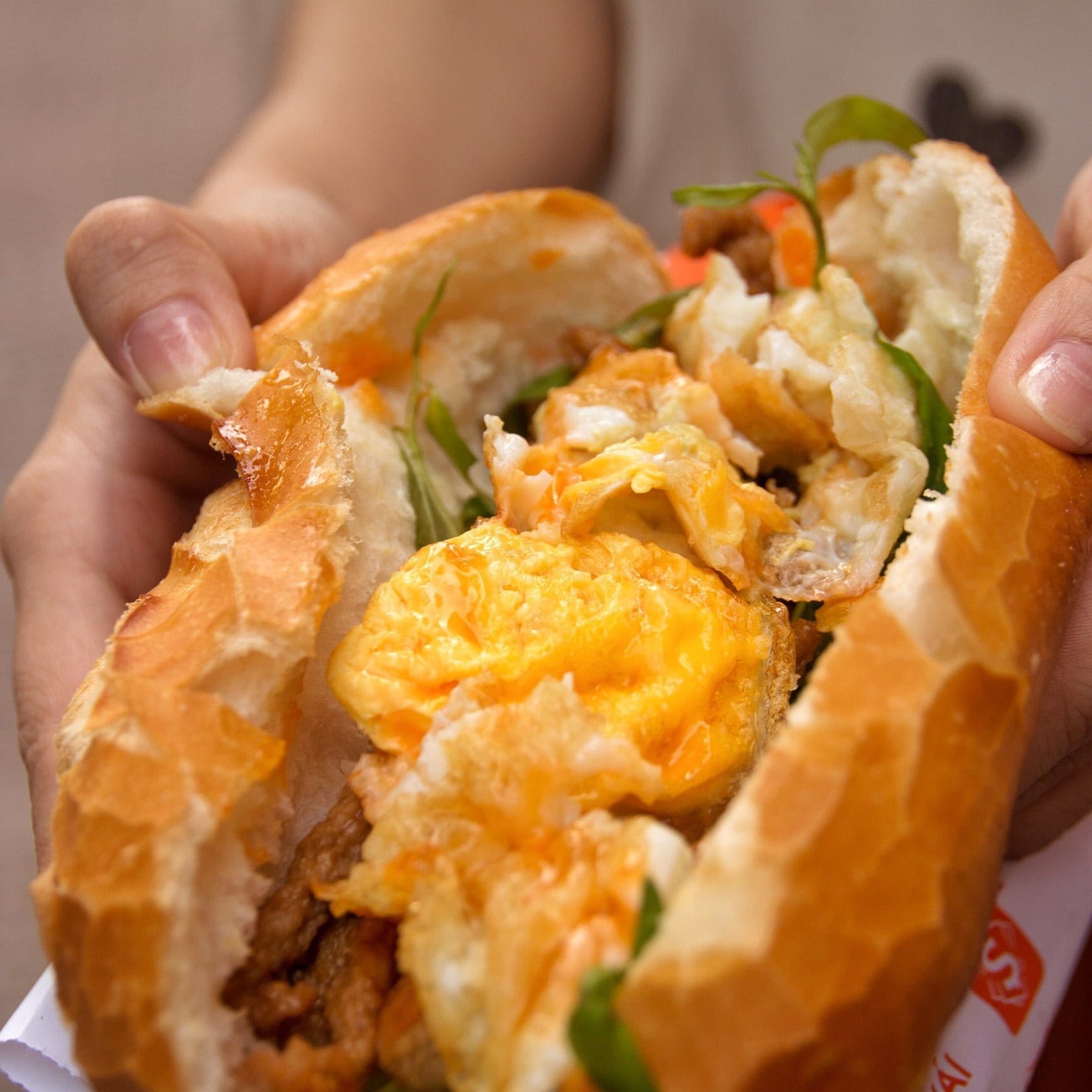 Crispy fried eggs served in small cast iron pan alongside fresh Vietnamese baguette